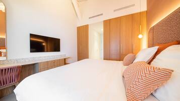 Une chambre à coucher moderne avec un grand lit, une armoire en bois et un téléviseur à écran plat fixé au mur.