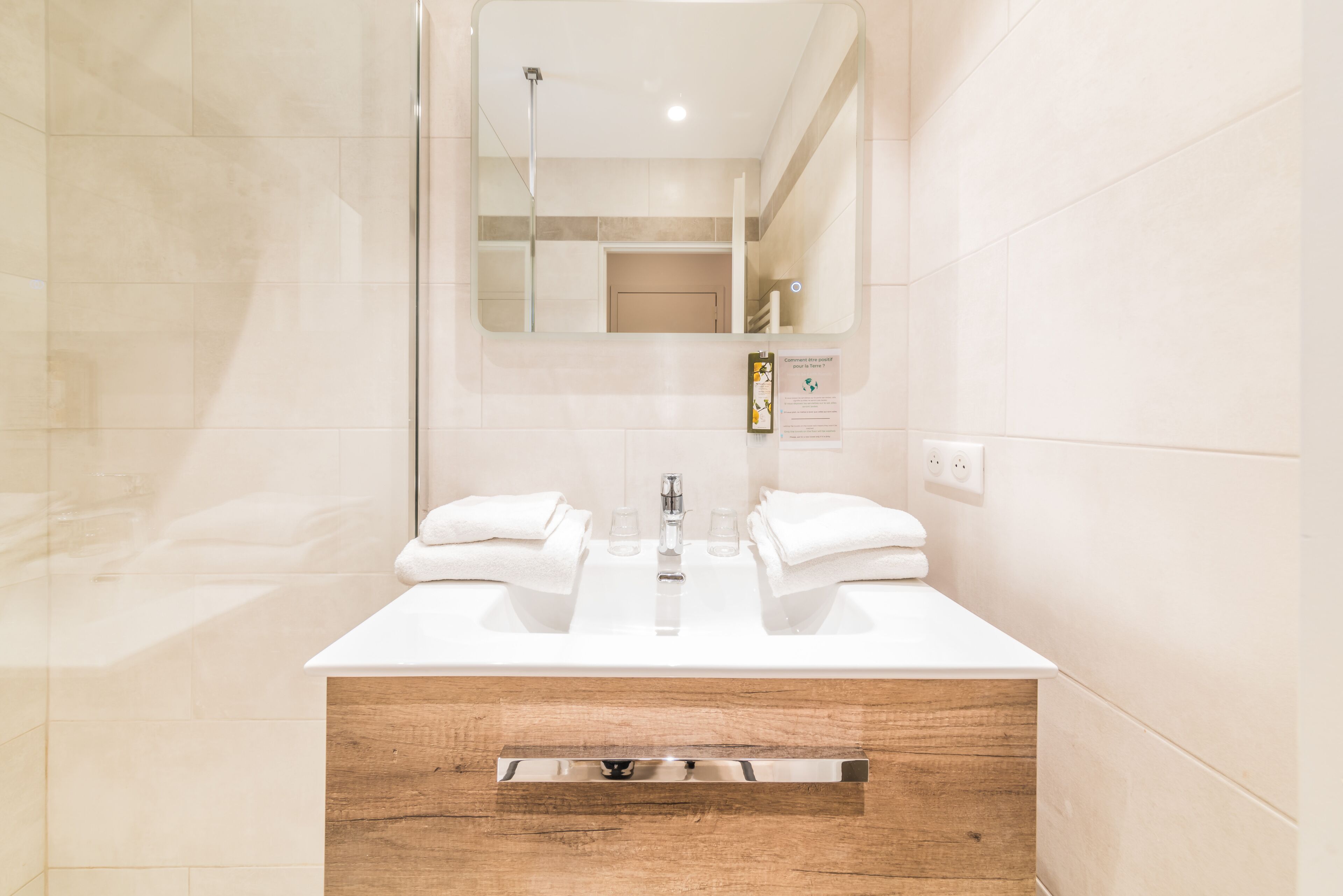 Une salle de bain moderne avec un double lavabo, un miroir et un meuble-lavabo en bois.
