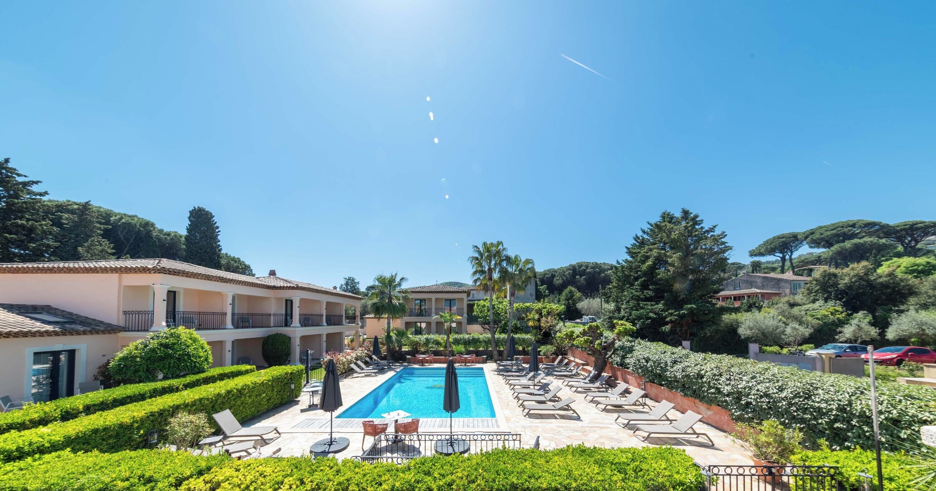 A pool area with lounge chairs and a clear blue sky.