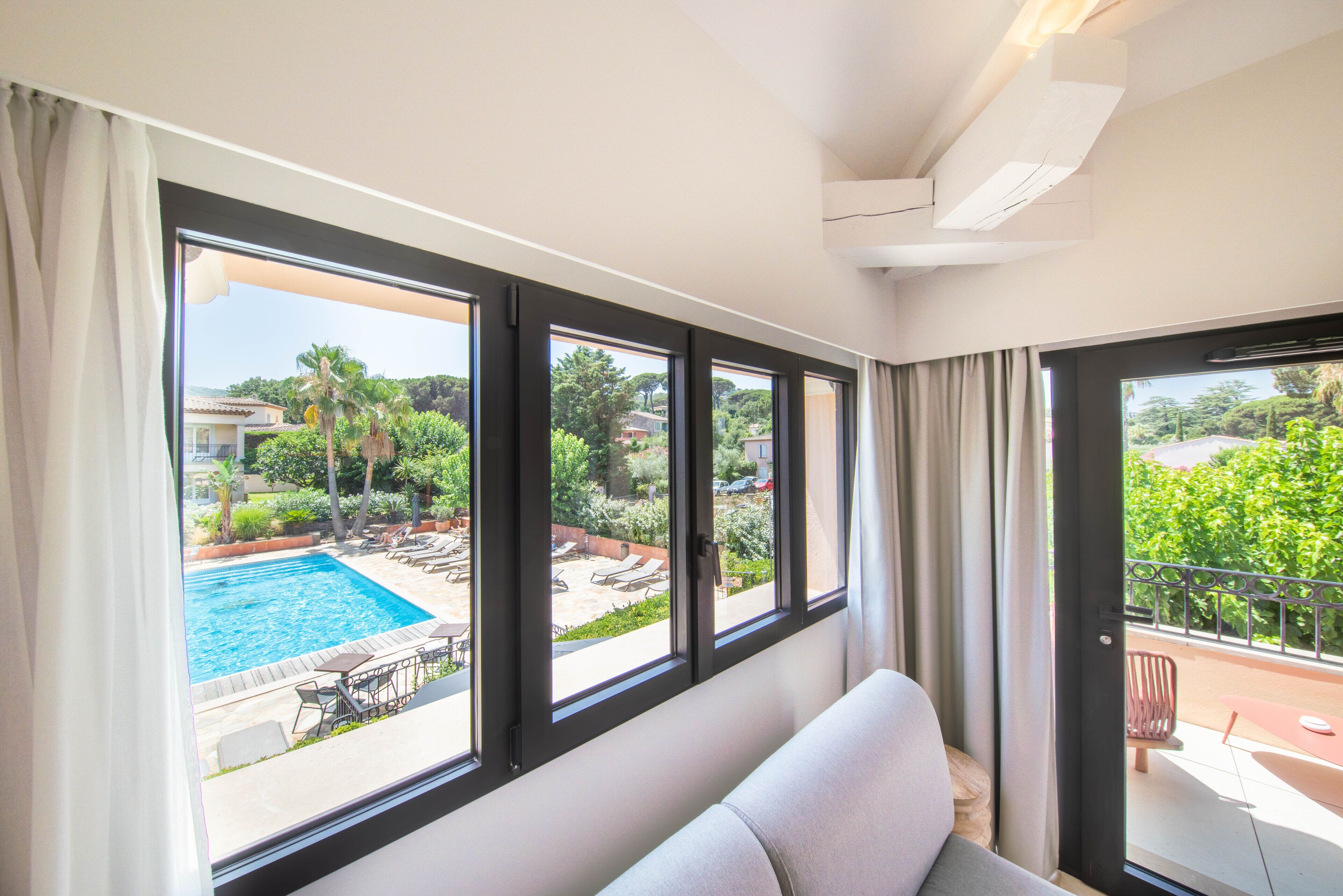A room with large windows overlooking a swimming pool and outdoor seating area.