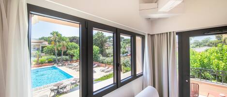 Ein Zimmer mit großen Fenstern, die einen Pool und eine Außenbereich-Sitzgelegenheit zeigen.