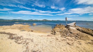 Uma praia rochosa com água cristalina e montanhas ao longe.