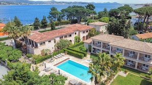 Área residencial com piscina, vegetação exuberante e vista para o mar.