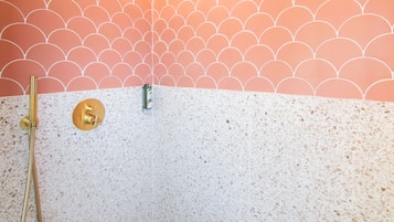 A shower with a scalloped pattern wall, a handheld showerhead, and a handheld shower attachment.