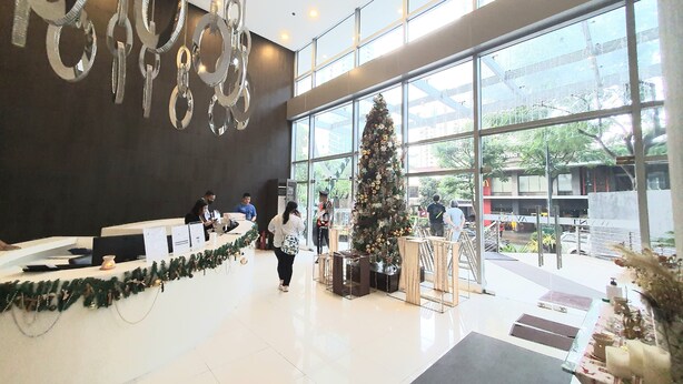 Un moderno vestíbulo de hotel con mostrador de recepción, ventanas amplias y un árbol de Navidad decorado.