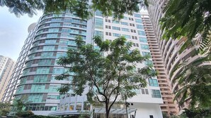 Un edificio moderno con fachada curva, rodeado de vegetación y un cielo despejado.