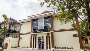 A building with a sign reading "OYO LIFE" at the entrance, featuring a large gate and a small garden area. - OYO Life 2735 Graha Nirwana (Batam)
