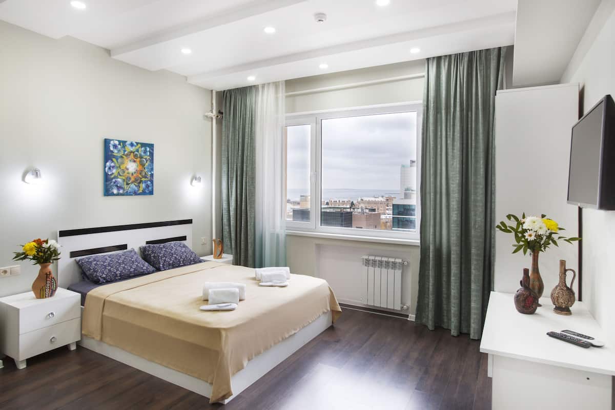 Une chambre d’hôtel moderne équipée d’un grand lit, d’un bureau, d’une télévision et d’une fenêtre avec des rideaux.