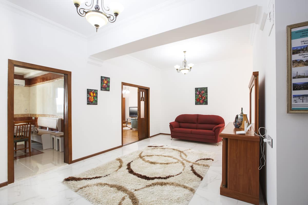 Un salon spacieux avec un canapé rouge, un meuble en bois et un lustre.