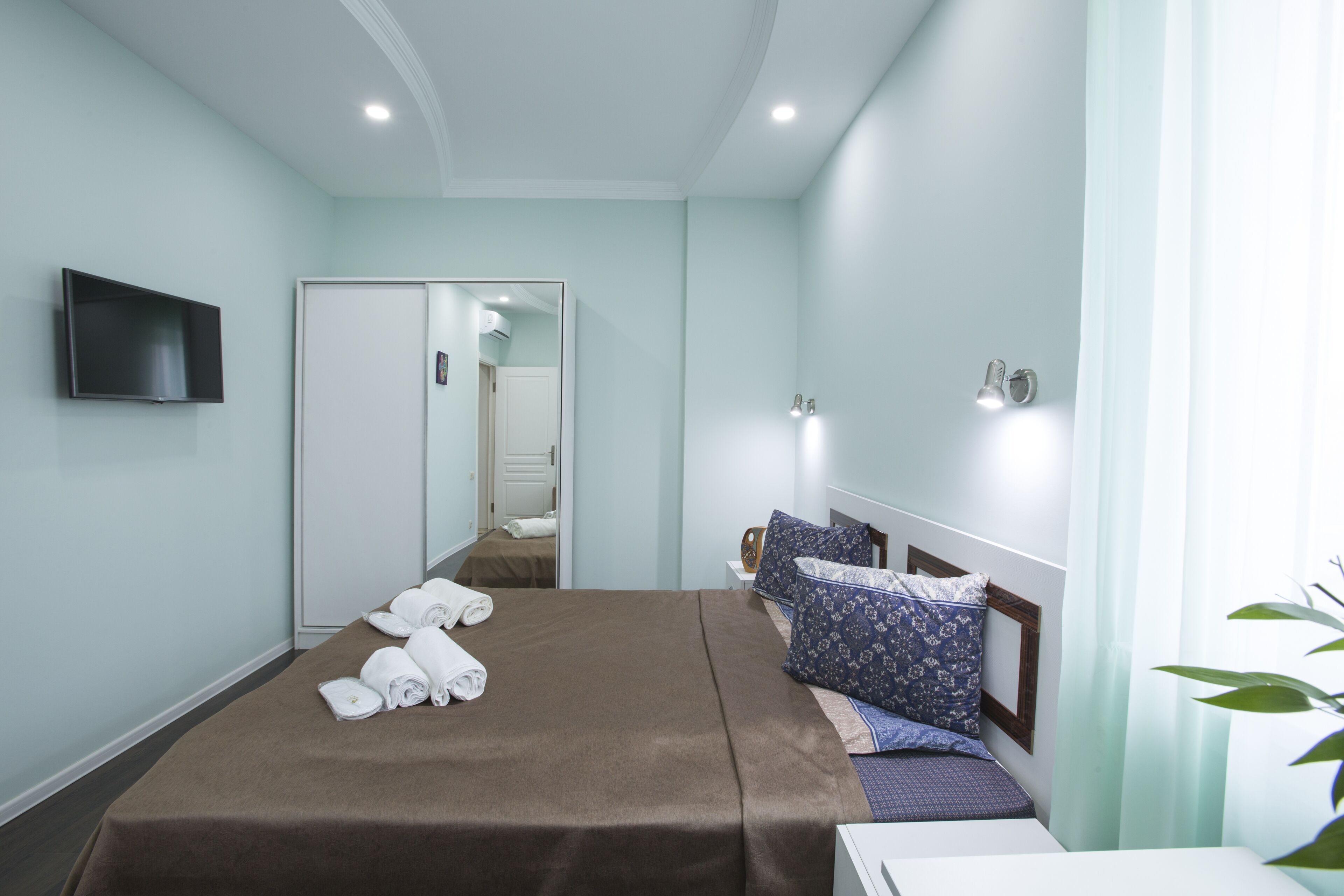 A hotel room with a bed, a TV, a wardrobe, and a mirror.