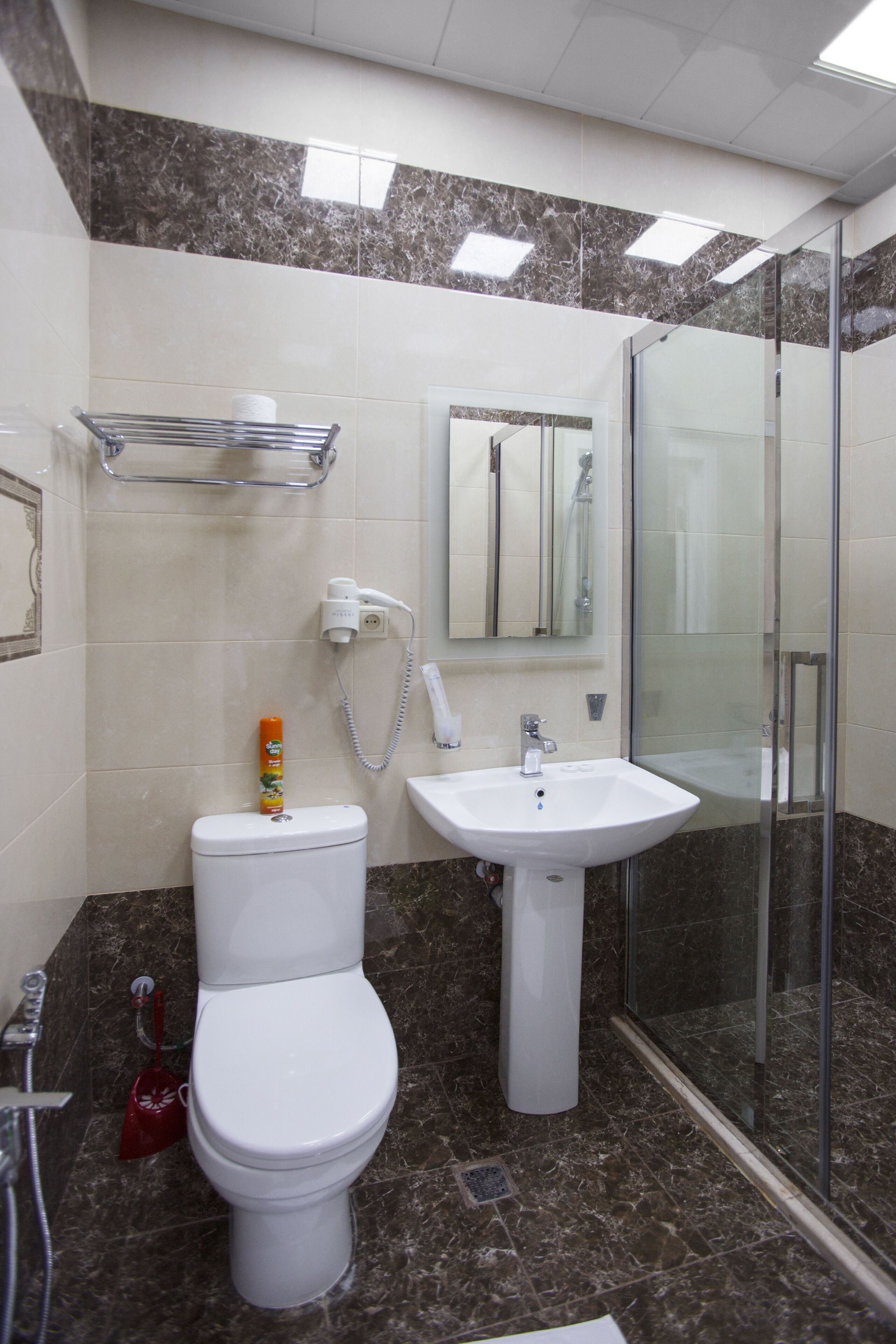 A bathroom with a toilet, sink, and glass shower enclosure.