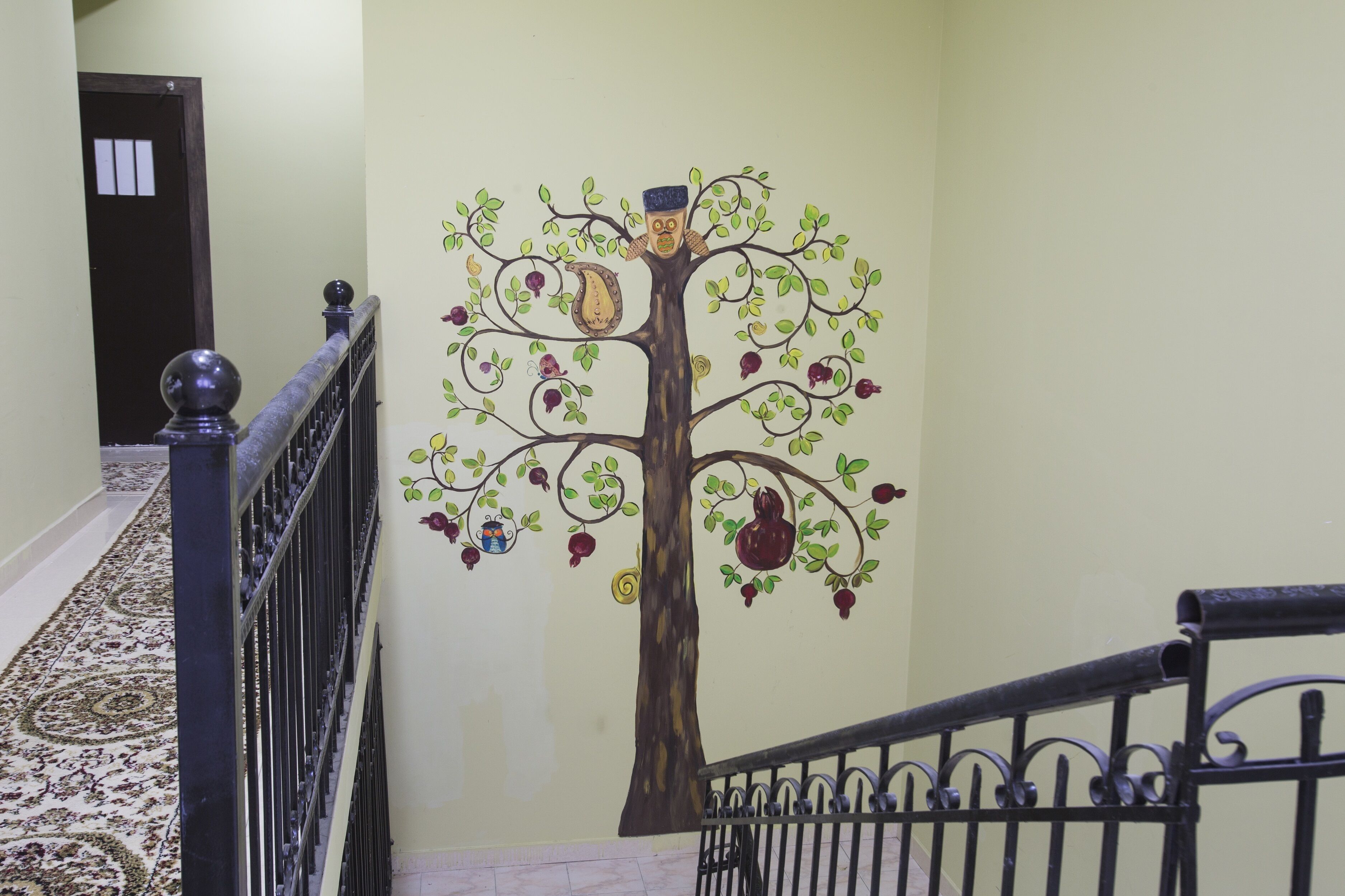 A staircase with a decorative tree mural on the wall.