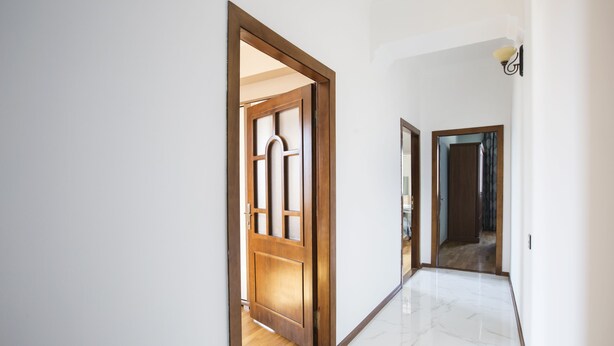 Un pasillo con puertas de madera y suelo de mármol.