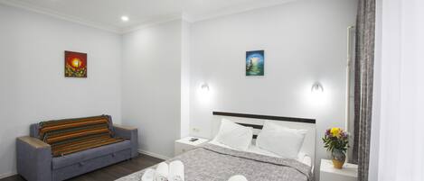 Une chambre d’hôtel avec un lit, un canapé, une table de chevet et un mur orné de deux tableaux.