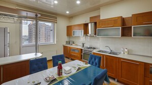 Una cocina moderna con armarios de madera, un refrigerador de acero inoxidable y una ventana con vistas a un paisaje urbano.