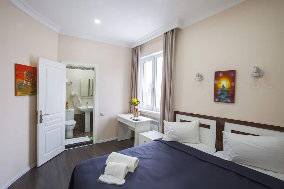 Une chambre d’hôtel avec un lit, une table de chevet et une fenêtre avec des rideaux.