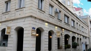Un edificio de varios pisos con un estilo arquitectónico clásico, que presenta arcos en las entradas y una fachada simétrica.