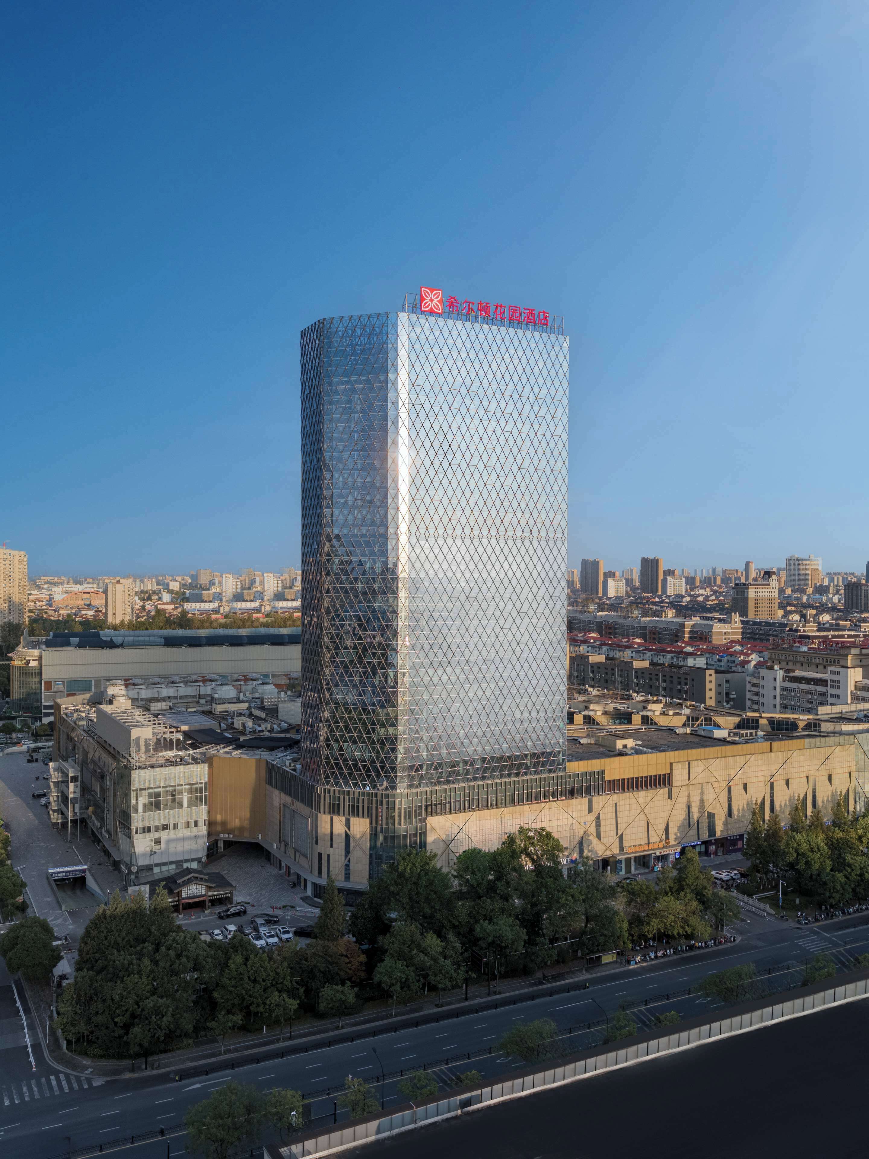 A modern skyscraper with a distinctive geometric facade, surrounded by a cityscape and a river.