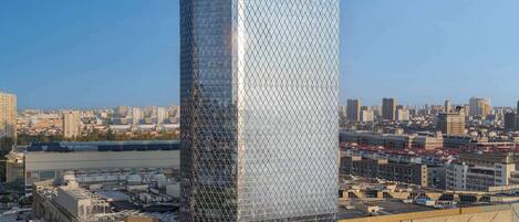 A modern skyscraper with a distinctive geometric facade, surrounded by a cityscape and a river.
