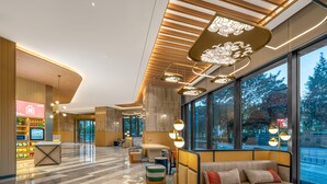 Un lobby moderno con zona de estar, mostrador de recepción y grandes ventanales con vistas al exterior.