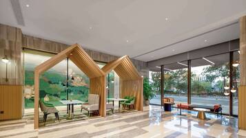A modern lobby with a geometric wooden structure, seating arrangements, and large windows offering a view of the street.
