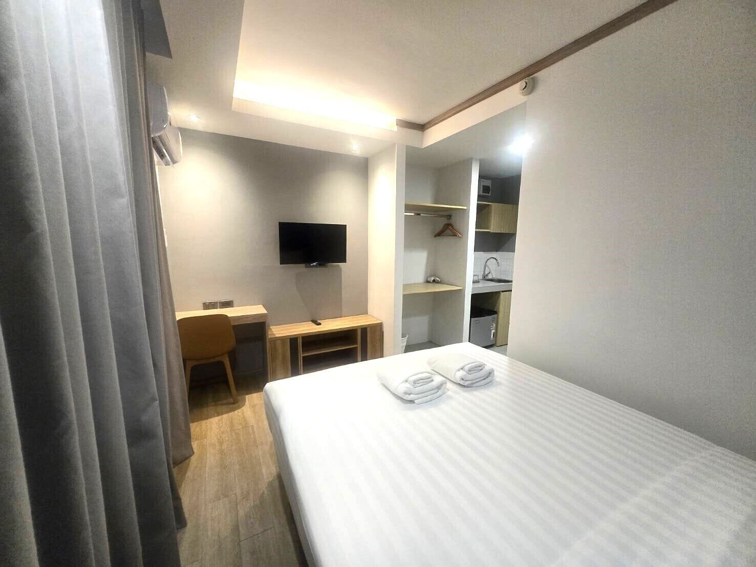Una habitación de hotel con cama, escritorio, televisión y vestidor.