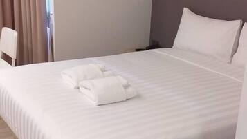 A hotel room with a bed, a wall-mounted air conditioner, and a window with curtains.