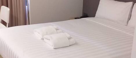 A hotel room with a bed, a wall-mounted air conditioner, and a window with curtains.