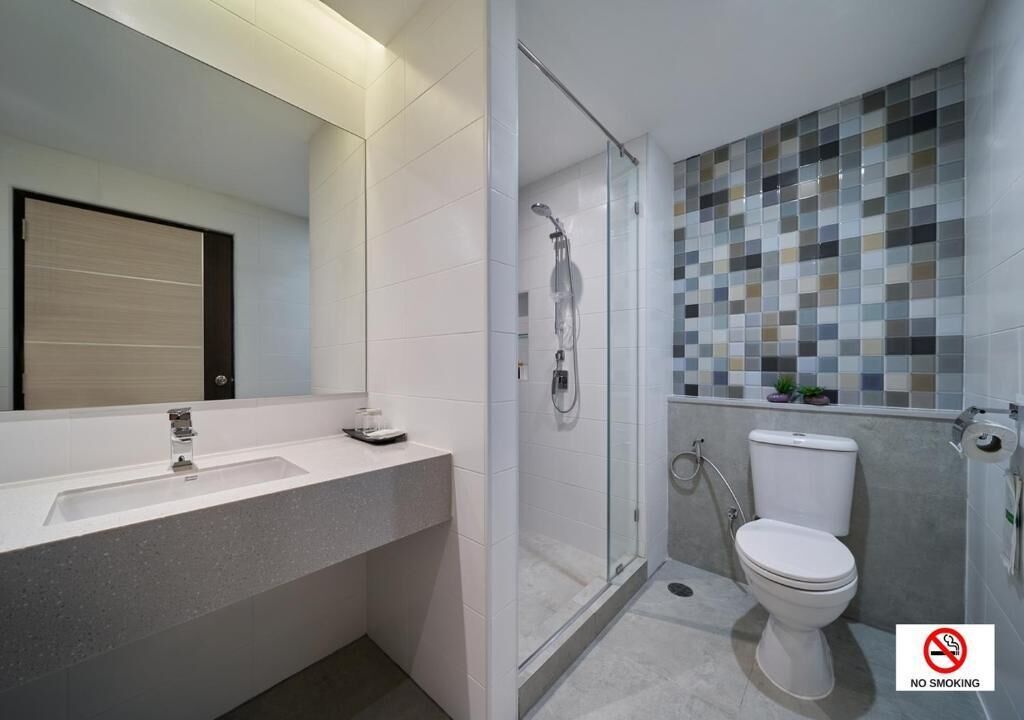 Et moderne badeværelse med vask i hvidt, en glasafskærmet bruseniche og et toilet.