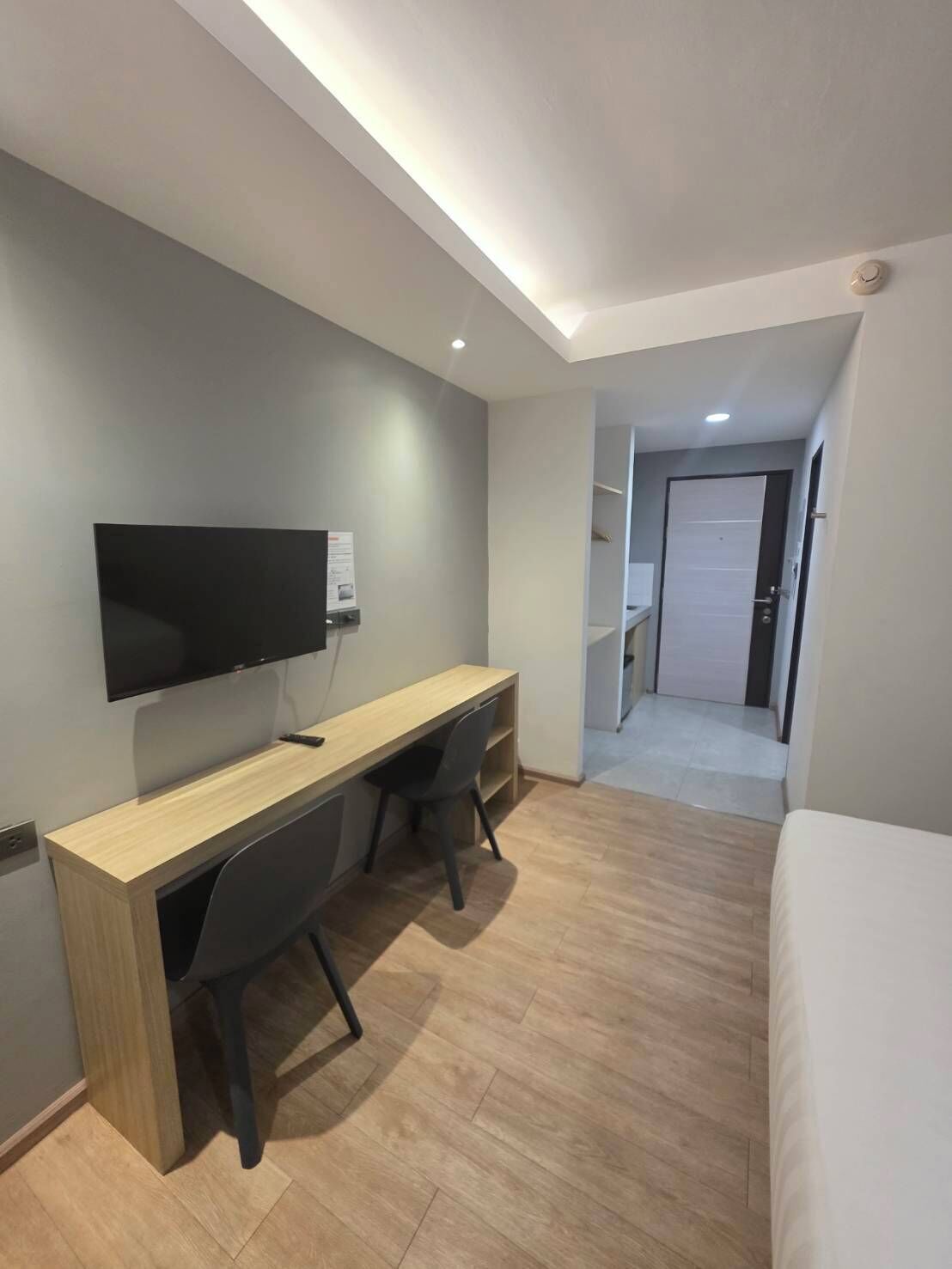 Une chambre d’hôtel moderne avec un bureau en bois, un téléviseur à écran plat et un lit.