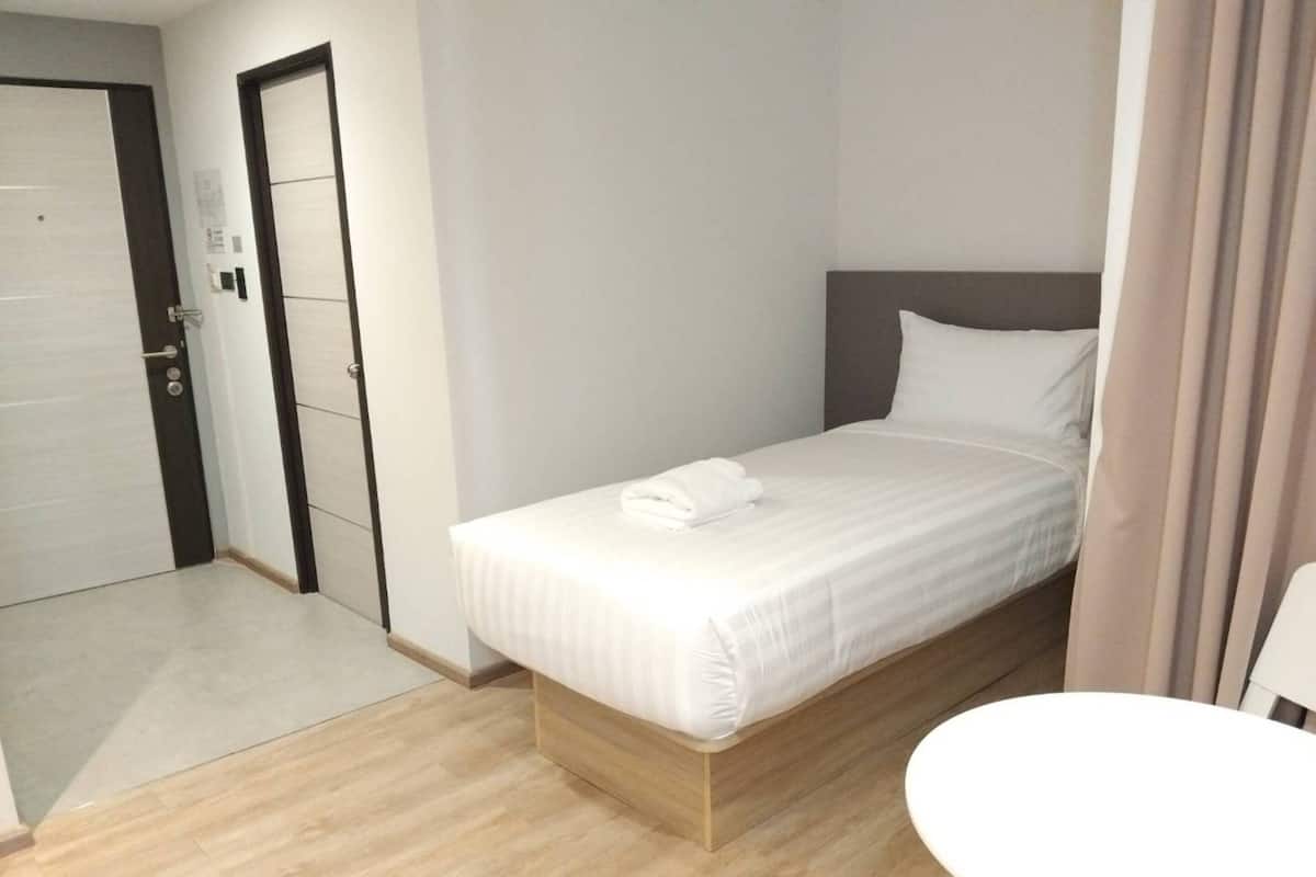 Une chambre d’hôtel avec un lit, une petite table ronde et une porte.