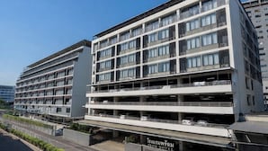 A multi-story hotel with a modern design, featuring balconies, a parking garage, and a clear sky. - Prom Thailand Cultural Centre Hotel Annex2 (Bangkok)