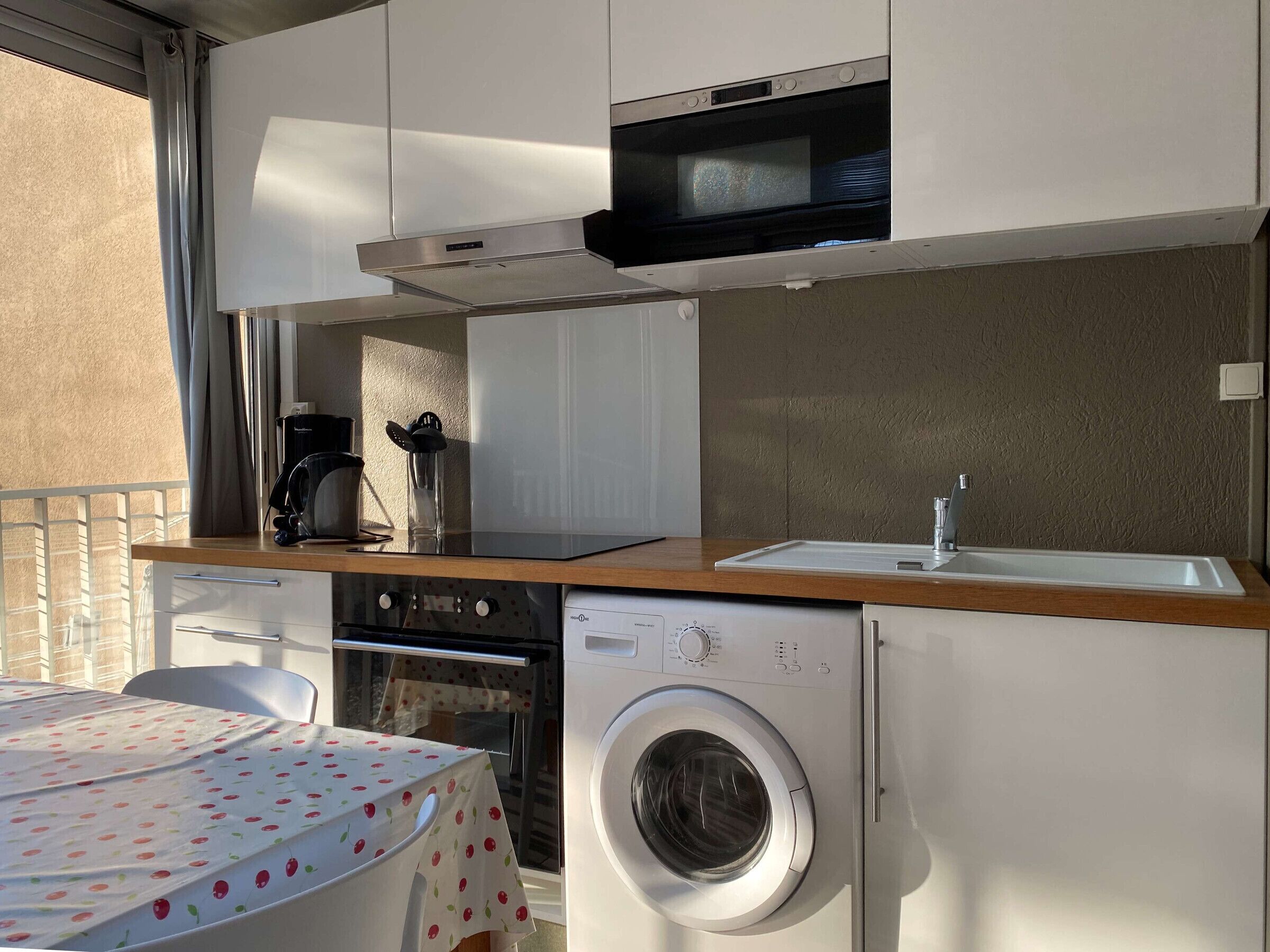 Une petite cuisine équipée d’un four à micro-ondes, d’un four et d’un lave-linge.