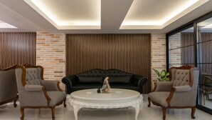 A modern living room with a black leather sofa, two grey armchairs, and a white coffee table. - Rubby Kadıköy (Istanbul)