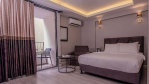 A modern hotel room with a large bed, a small round table, a chair, and a balcony with a view. - Rubby Kadıköy (Istanbul)