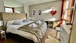 A well-lit bedroom with a large bed, a bedside table, a dresser, and a mirror. - Luxury 4beds ski-in&out steps from center     (cervinia)