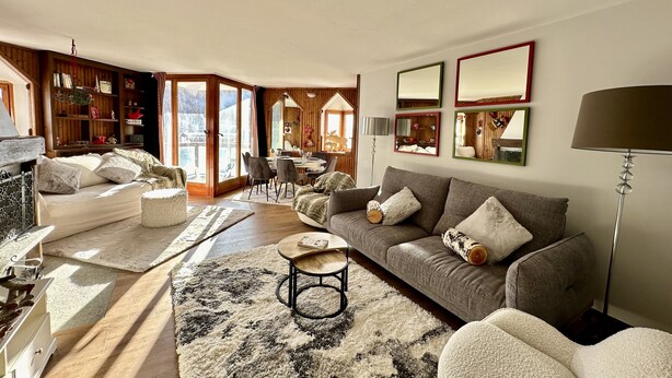 A cozy living room with a sofa, armchairs, a coffee table, and a fireplace. There is a dining area with a table and chairs, and a bookshelf filled with books and decorative items. - Luxury 4beds ski-in&out steps from center     (cervinia)