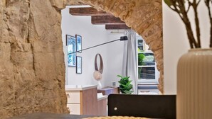 A rustic interior with a stone archway, woven placemats on a table, and a potted plant. - Charming Grund Retreat Near Neumünster Abbey (Luxembourg)