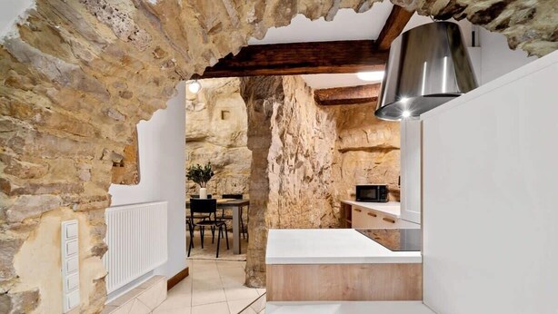 A rustic kitchen with exposed stone walls, a wooden counter, and a modern stainless steel range hood. - Charming Grund Retreat Near Neumünster Abbey (Luxembourg)