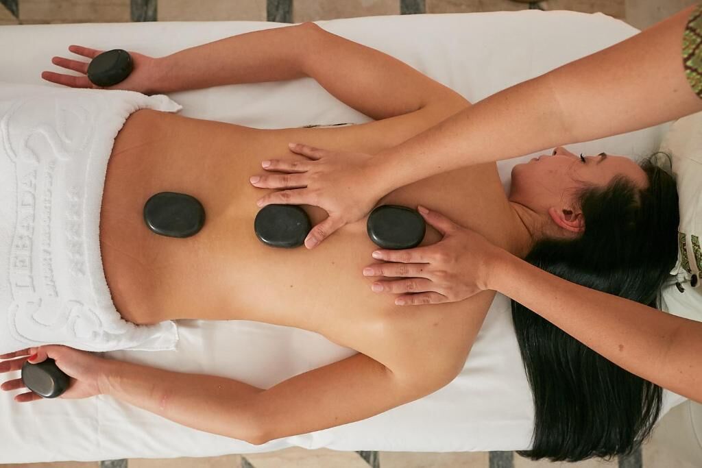 Een persoon ontvangt een rugmassage met twee stenen op de rug.