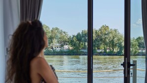 A room with a bed, a view of a body of water, and a door leading outside. - Lebada Luxury Resort & Spa (Crisan)