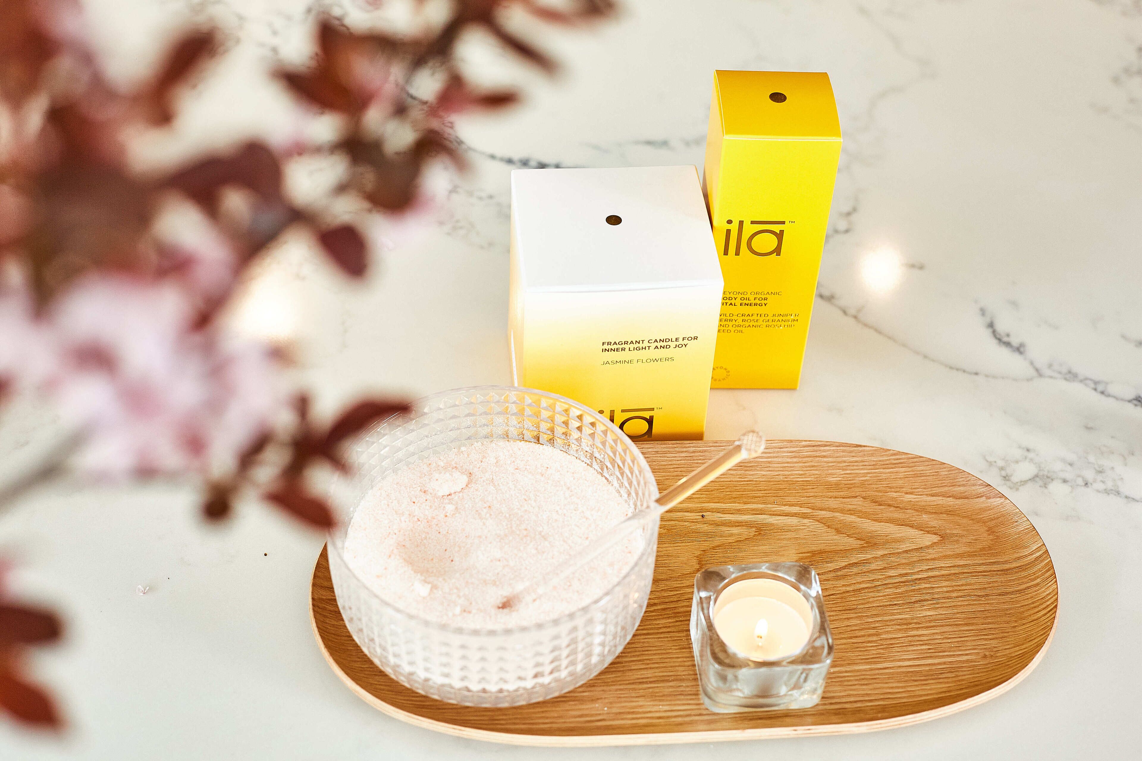 A candle, a box, and a bowl on a wooden tray.