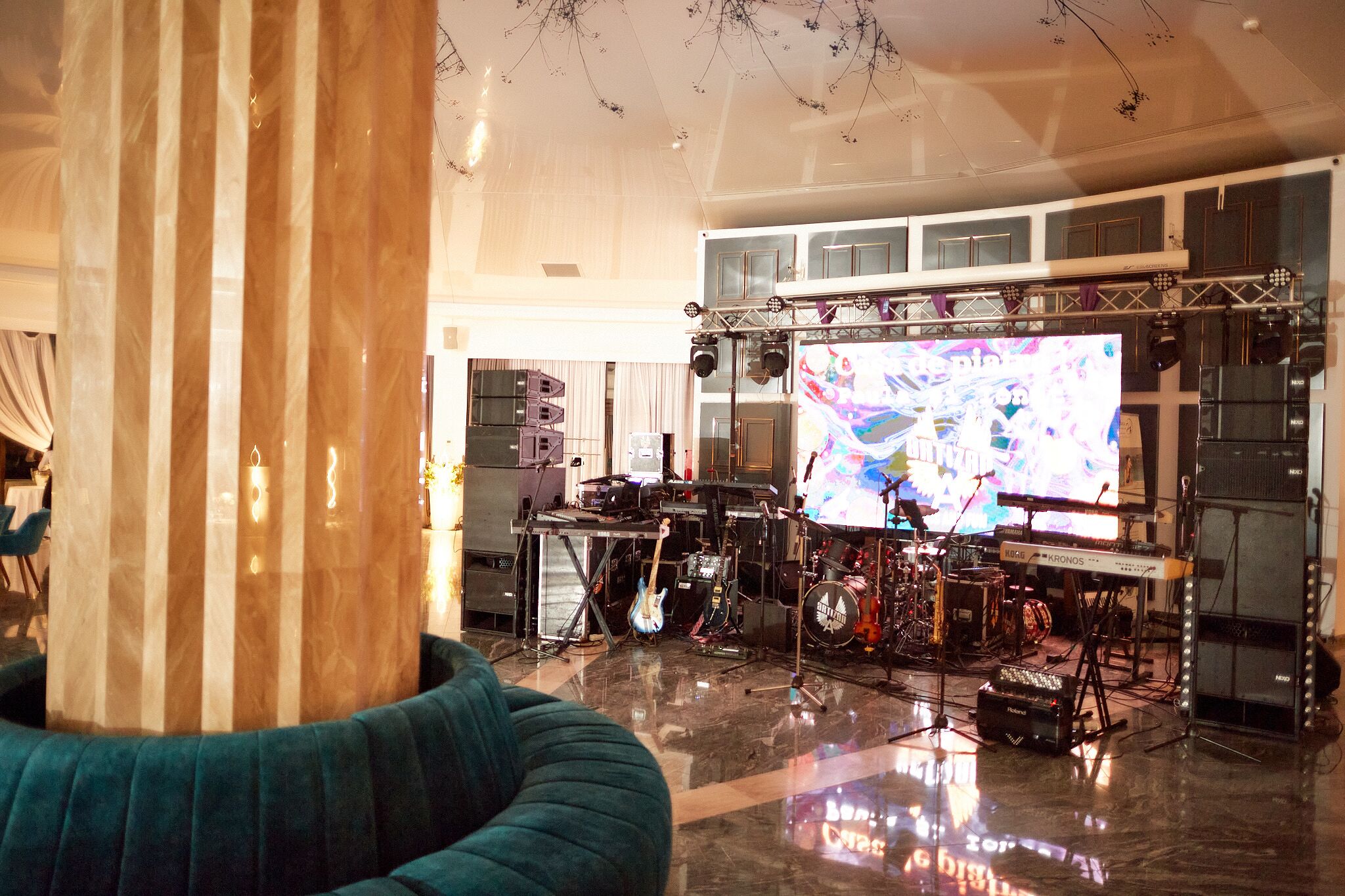 A spacious room with a stage setup for live music, including a keyboard, drums, and guitars.
