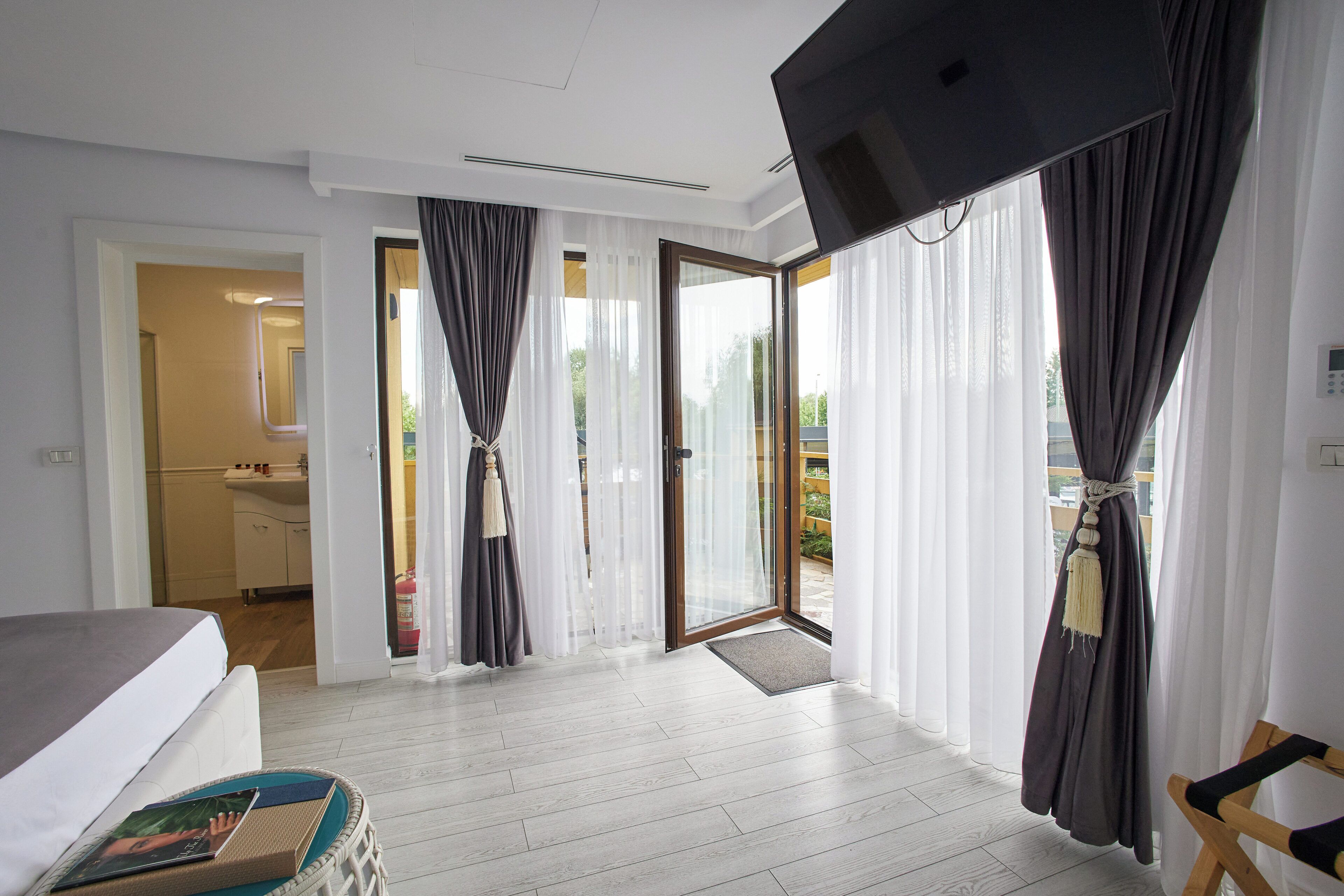 Ein Hotelzimmer mit Bett, einem kleinen Tisch, einem Fernseher und Blick nach draußen.