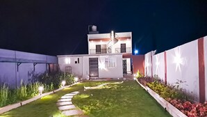 A modern two-story house with a well-maintained lawn and a pathway leading to the entrance. - Roomshala 135 Paradise Villa Banglore (Devanahalli)