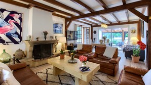 A spacious living room with a fireplace, leather sofas, and a wooden ceiling. - Villa 'Rodolphe' with Private Pool, Private Terrace, and Wi-Fi (Le Pian-Médoc)