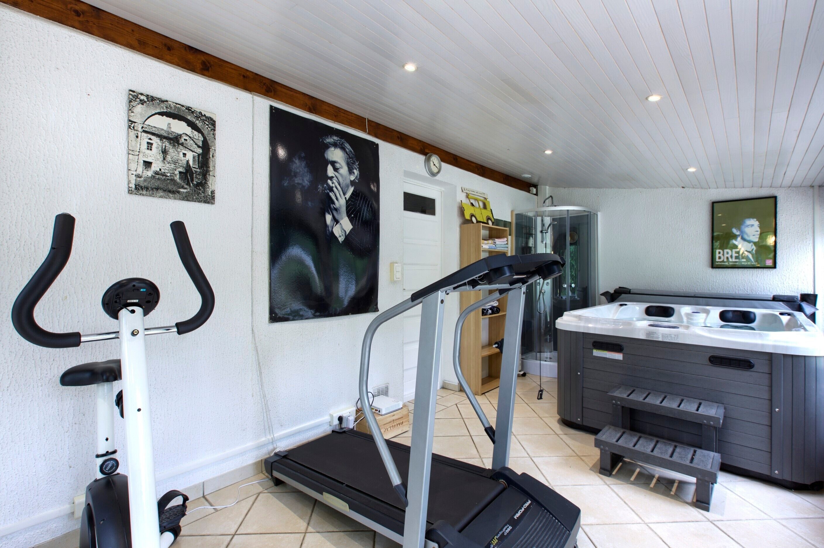 Une salle de sport à domicile équipée d’un tapis de course, d’un vélo d’appartement et d’un jacuzzi.