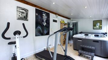 Une salle de sport à domicile équipée d’un tapis de course, d’un vélo d’appartement et d’un jacuzzi.