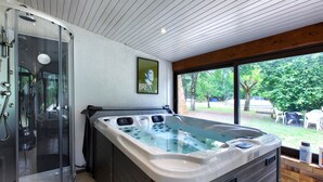 A spa area with a glass-enclosed shower, a hot tub, and a view of the outdoors. - Villa 'Rodolphe' with Private Pool, Private Terrace, and Wi-Fi (Le Pian-Médoc)