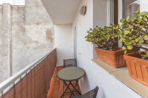 Un petit balcon avec une table et deux plantes en pot.